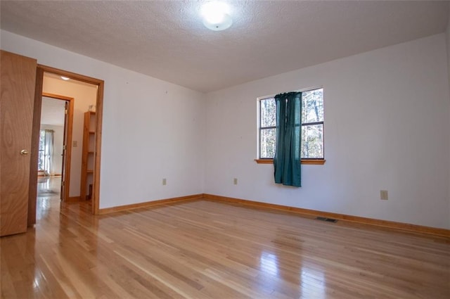 empty room featuring light wood-type flooring and a textured ceiling