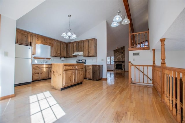 kitchen with an inviting chandelier, a stone fireplace, white refrigerator, light hardwood / wood-style floors, and pendant lighting