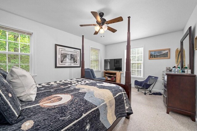 bedroom featuring ceiling fan, light carpet, and multiple windows