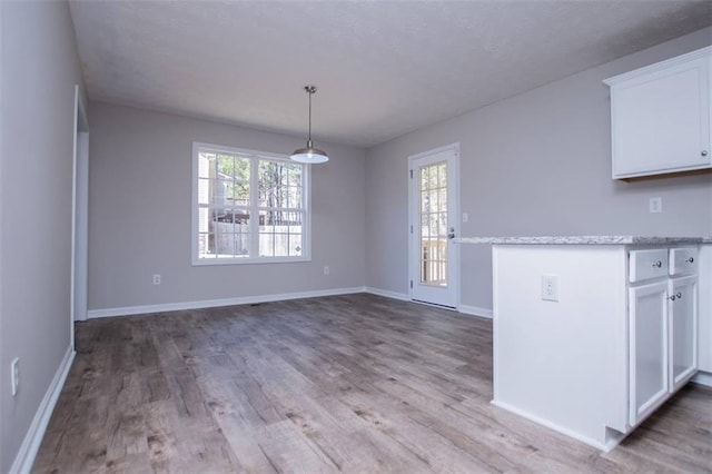 unfurnished dining area featuring baseboards, a textured ceiling, and wood finished floors