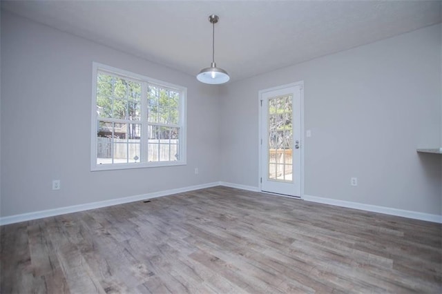 unfurnished room featuring a wealth of natural light, baseboards, and wood finished floors