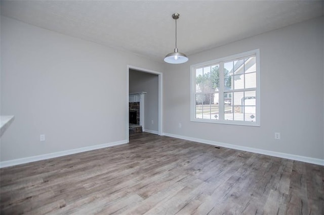 unfurnished dining area featuring baseboards, wood finished floors, and a fireplace