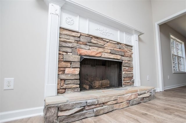 room details with a stone fireplace, baseboards, and wood finished floors