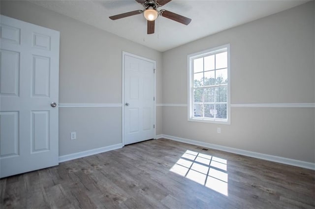 unfurnished bedroom with a ceiling fan, wood finished floors, and baseboards