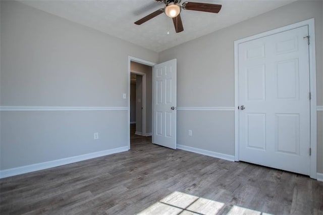 unfurnished bedroom with a ceiling fan, wood finished floors, and baseboards