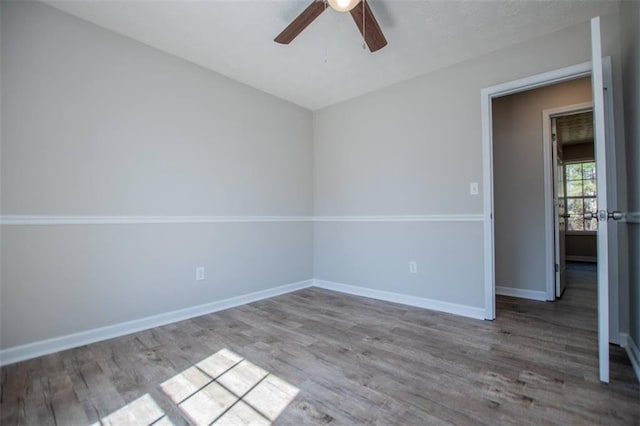 spare room with baseboards, wood finished floors, and ceiling fan