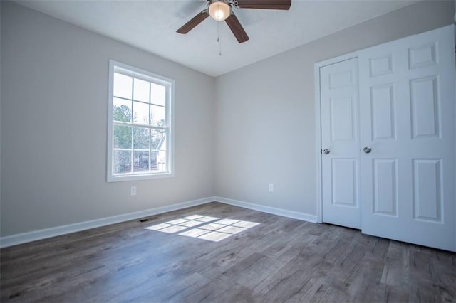 unfurnished bedroom featuring visible vents, wood finished floors, baseboards, and ceiling fan