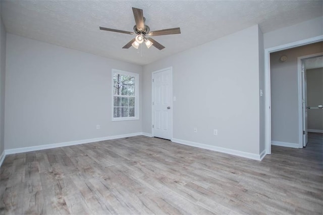 empty room with a textured ceiling, baseboards, a ceiling fan, and wood finished floors