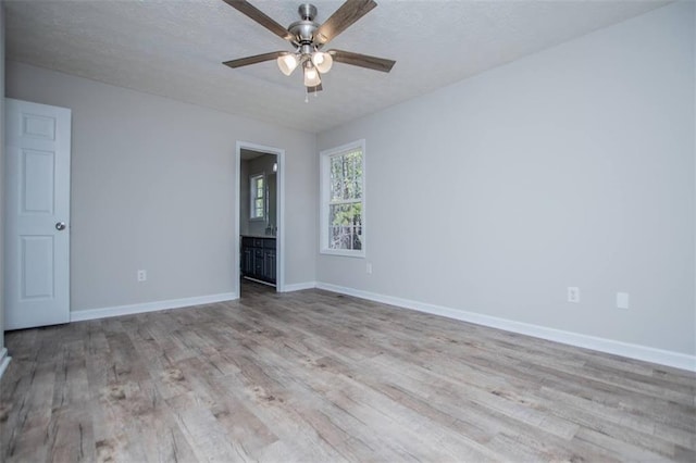 empty room with a textured ceiling, baseboards, ceiling fan, and wood finished floors