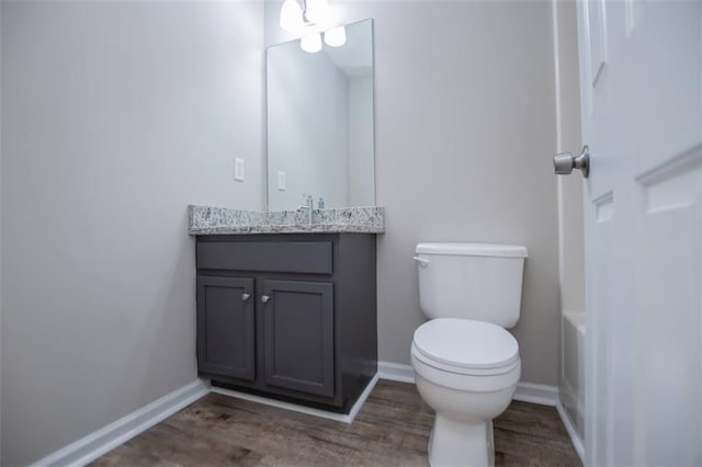 bathroom featuring toilet, vanity, baseboards, and wood finished floors