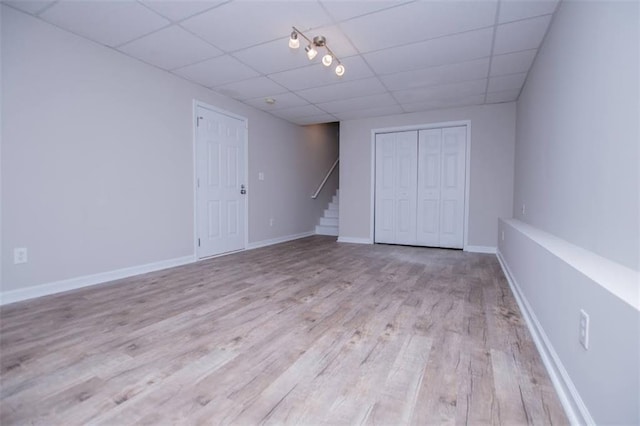 interior space featuring wood finished floors, stairway, a paneled ceiling, and baseboards