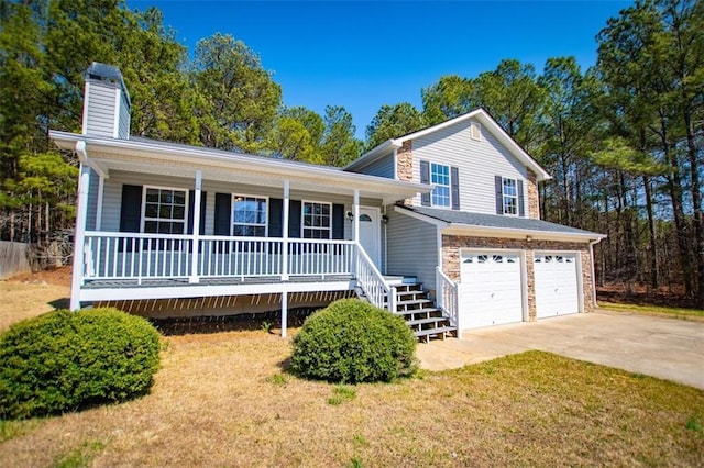 tri-level home with a porch, a chimney, driveway, and a garage