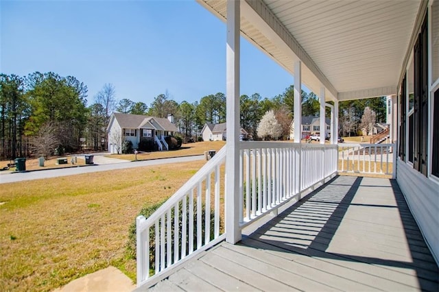 wooden terrace featuring a lawn and a porch