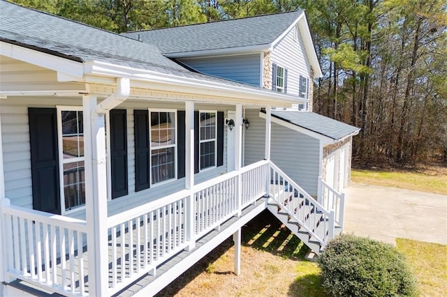 view of side of home featuring a porch and roof with shingles