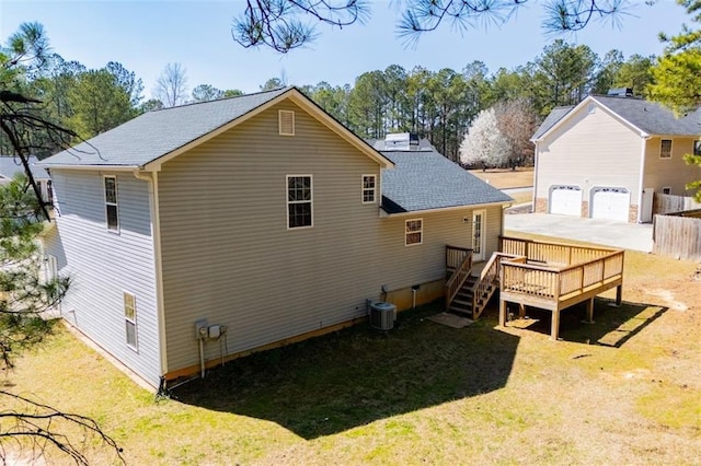 rear view of house featuring a deck, central AC, a yard, a shingled roof, and a garage