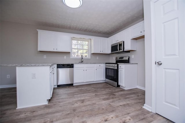 kitchen featuring white cabinets, light wood-style flooring, and stainless steel appliances