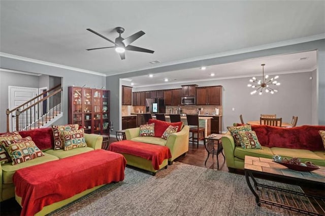 living area featuring stairway, wood finished floors, crown molding, and ceiling fan with notable chandelier