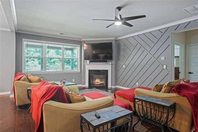 living room with dark wood finished floors, crown molding, visible vents, a glass covered fireplace, and baseboards