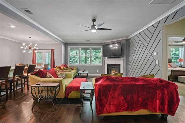 living room featuring ceiling fan with notable chandelier, dark wood-type flooring, visible vents, and crown molding