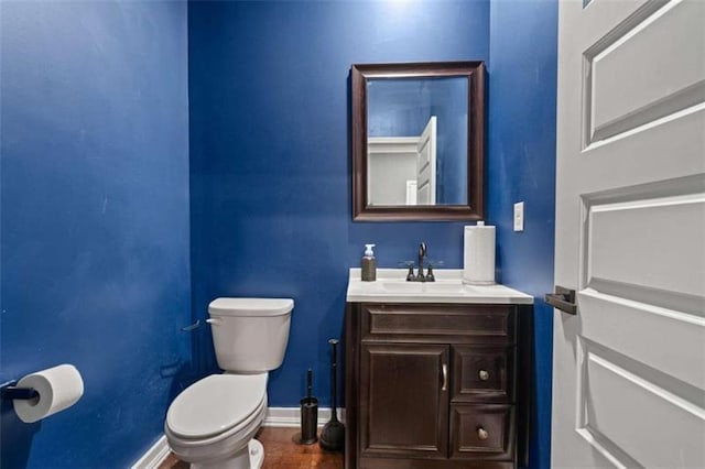 bathroom with baseboards, vanity, toilet, and wood finished floors