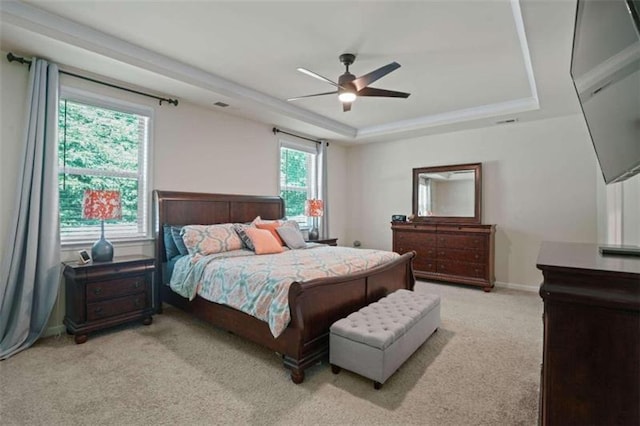 bedroom with baseboards, a raised ceiling, a ceiling fan, and light colored carpet