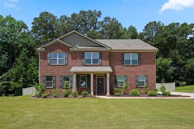 view of front of home featuring a front lawn, board and batten siding, fence, and brick siding