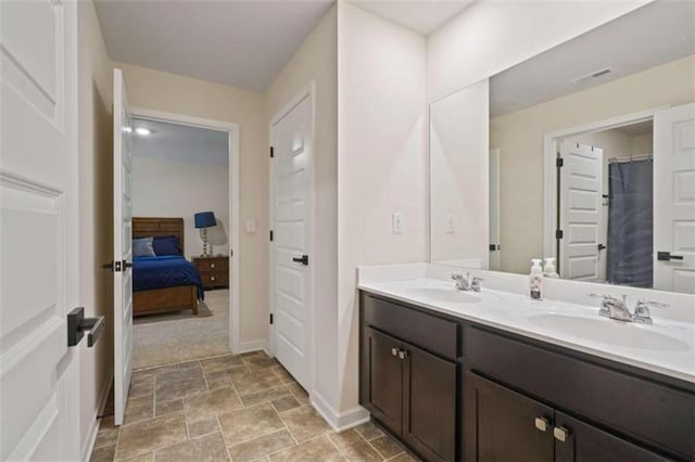 ensuite bathroom featuring double vanity, a sink, visible vents, and connected bathroom