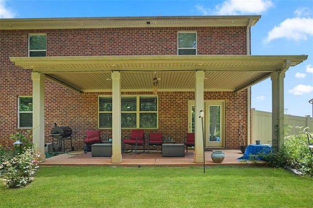 back of house with a patio area, a lawn, an outdoor living space, and brick siding