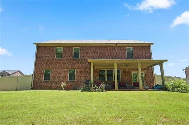 back of house with brick siding, a lawn, and fence