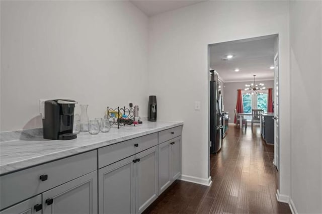 bar with baseboards, dark wood finished floors, freestanding refrigerator, a notable chandelier, and recessed lighting