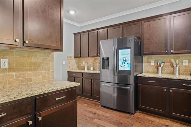 kitchen with dark brown cabinets, ornamental molding, light wood-type flooring, and stainless steel fridge with ice dispenser