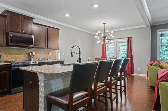 kitchen featuring pendant lighting, a breakfast bar area, stainless steel appliances, decorative backsplash, and a kitchen island with sink