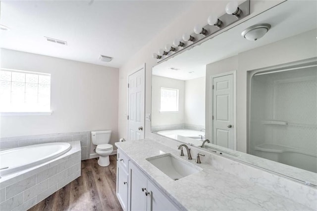 bathroom with vanity, tiled bath, toilet, and hardwood / wood-style flooring