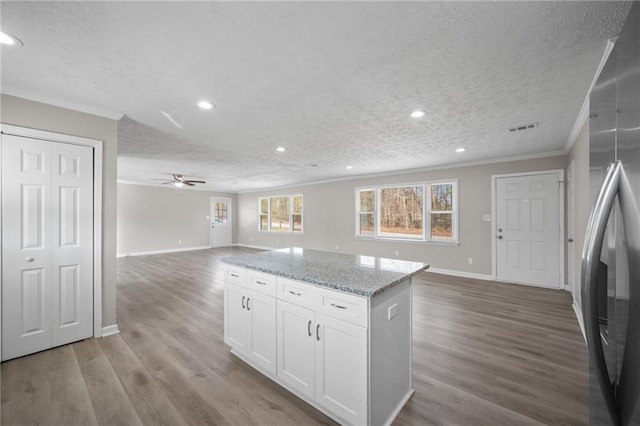 kitchen with wood finished floors, ornamental molding, ceiling fan, stainless steel refrigerator with ice dispenser, and open floor plan