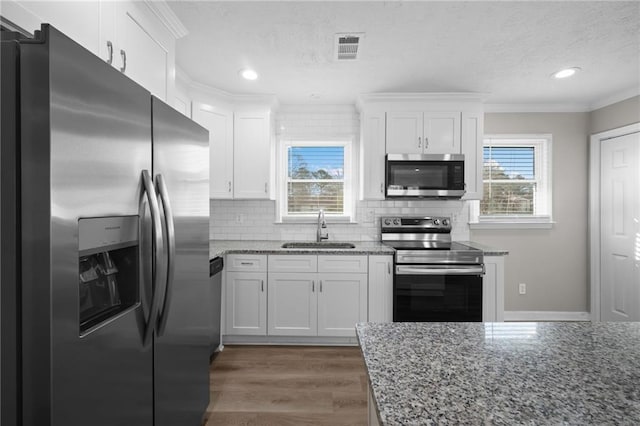 kitchen with visible vents, dark wood finished floors, ornamental molding, appliances with stainless steel finishes, and a sink