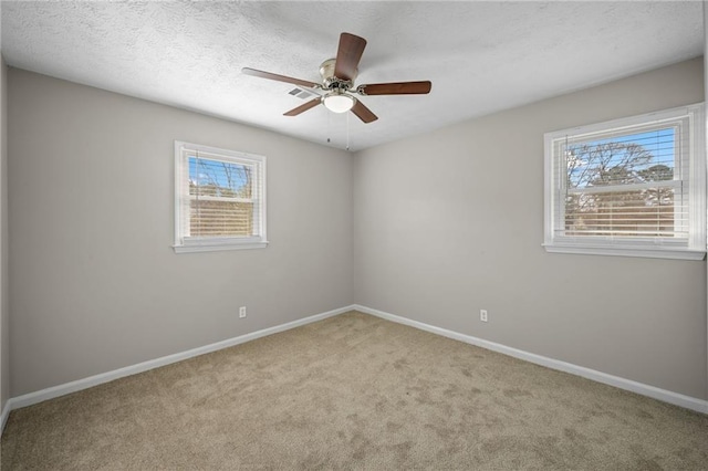 carpeted spare room featuring baseboards, a textured ceiling, and ceiling fan