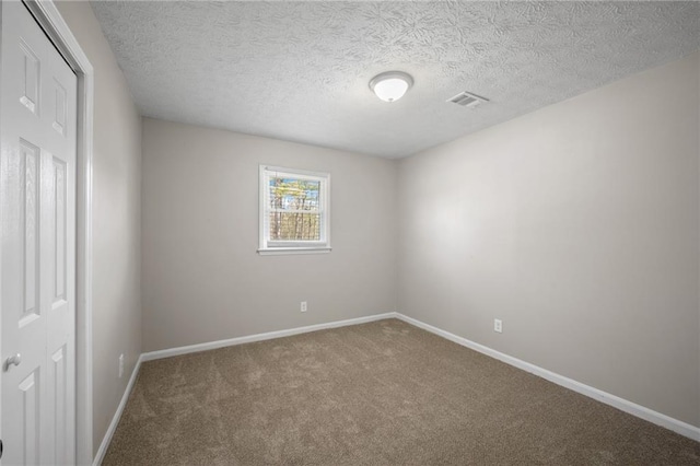 carpeted empty room with visible vents, a textured ceiling, and baseboards