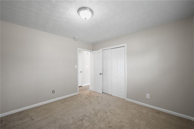 unfurnished bedroom with a closet, baseboards, carpet, and a textured ceiling