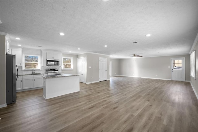 kitchen with a kitchen island, ceiling fan, wood finished floors, stainless steel appliances, and a sink