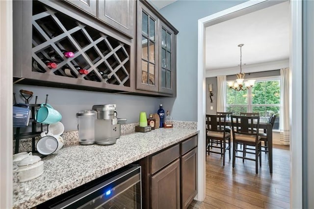 bar with beverage cooler, an inviting chandelier, and dark brown cabinetry