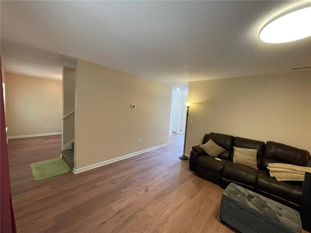 living room featuring wood finished floors, stairs, and baseboards