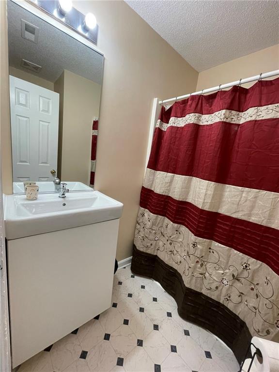 bathroom featuring a textured ceiling, vanity, and curtained shower