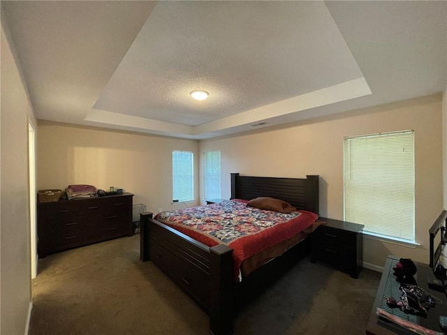 carpeted bedroom with a tray ceiling, baseboards, and a textured ceiling