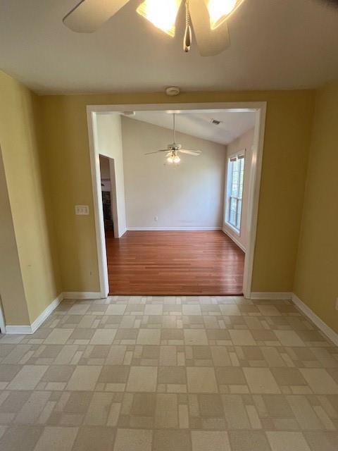 unfurnished room with baseboards, vaulted ceiling, visible vents, and a ceiling fan