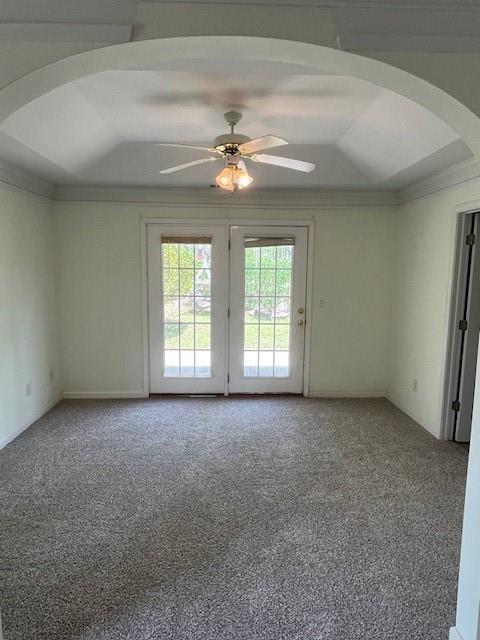 spare room with light carpet, ornamental molding, arched walkways, and ceiling fan
