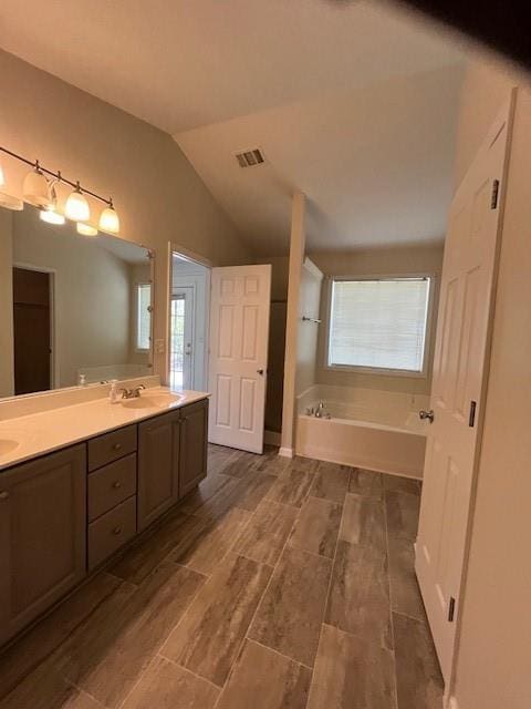 full bathroom featuring a healthy amount of sunlight, vaulted ceiling, visible vents, and a garden tub