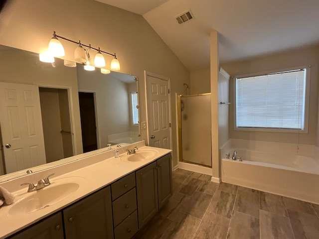 full bath with lofted ceiling, a sink, a garden tub, and a shower stall