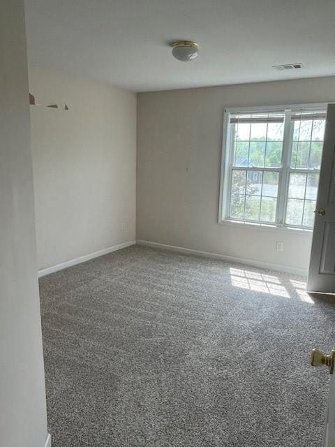 unfurnished room featuring baseboards, visible vents, and carpet