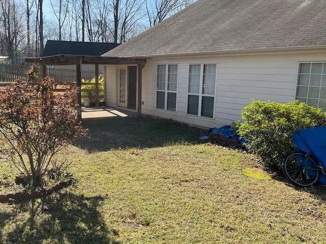 back of house with a lawn, a patio area, and roof with shingles