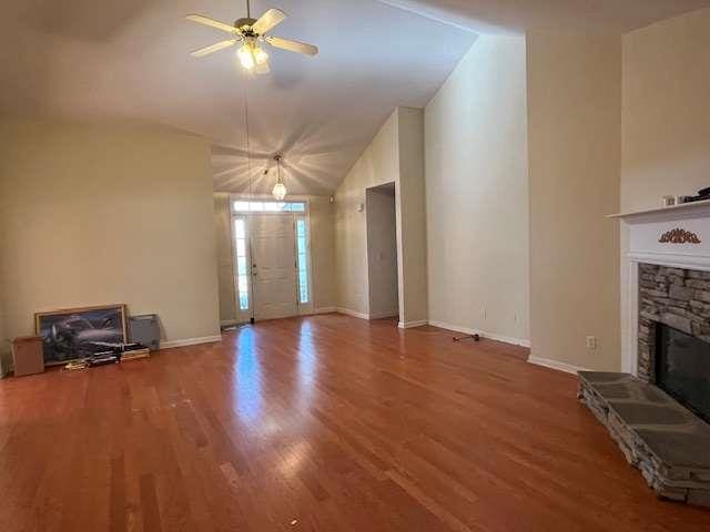 unfurnished living room featuring a fireplace, high vaulted ceiling, wood finished floors, and ceiling fan